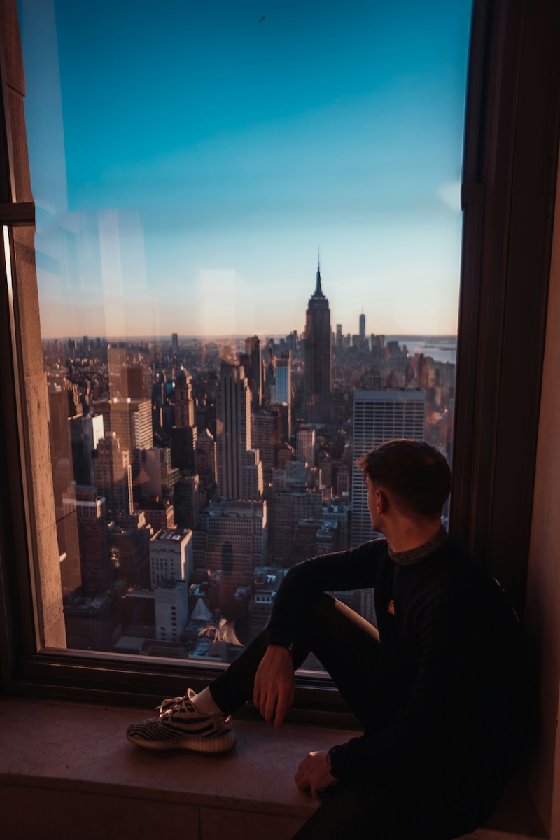 man looking out of window to NYC skyline